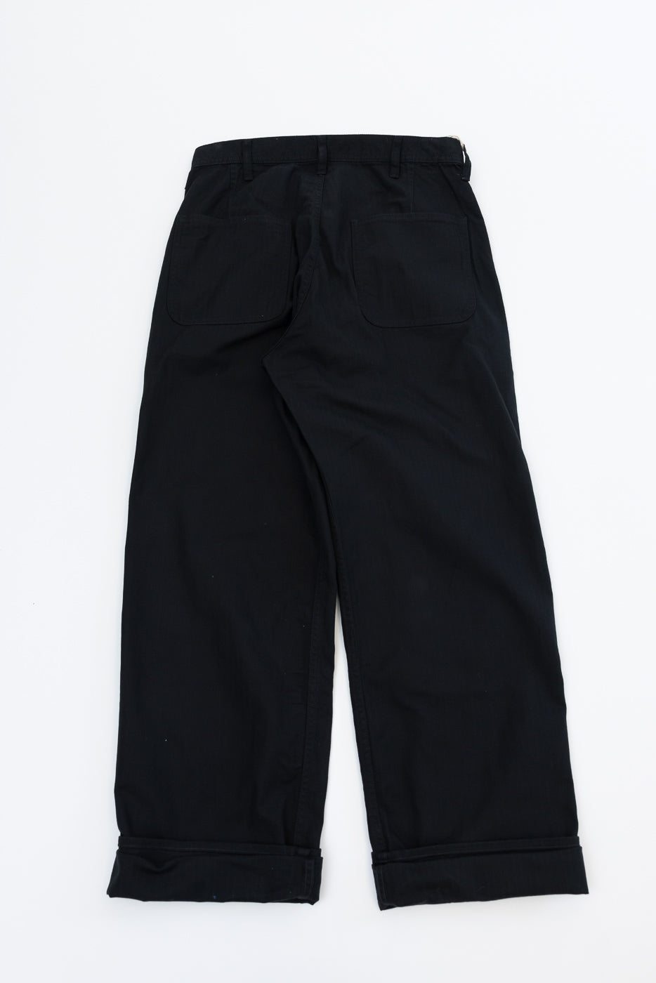 Back view of black wide-leg pants with cuffed hems and two rear pockets, flat lay