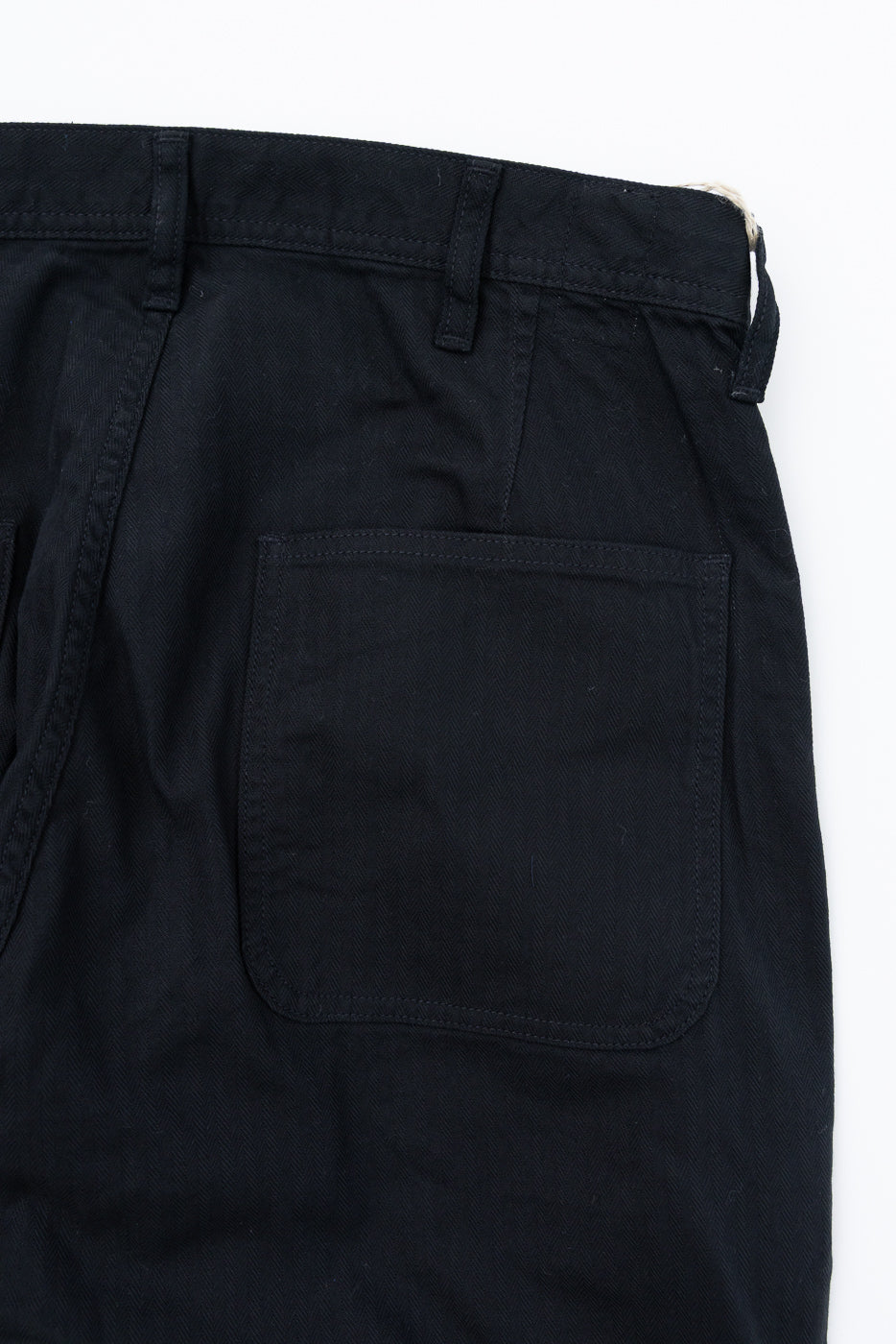 Close-up of black selvedge pants back pocket, waistband, and stitching detail