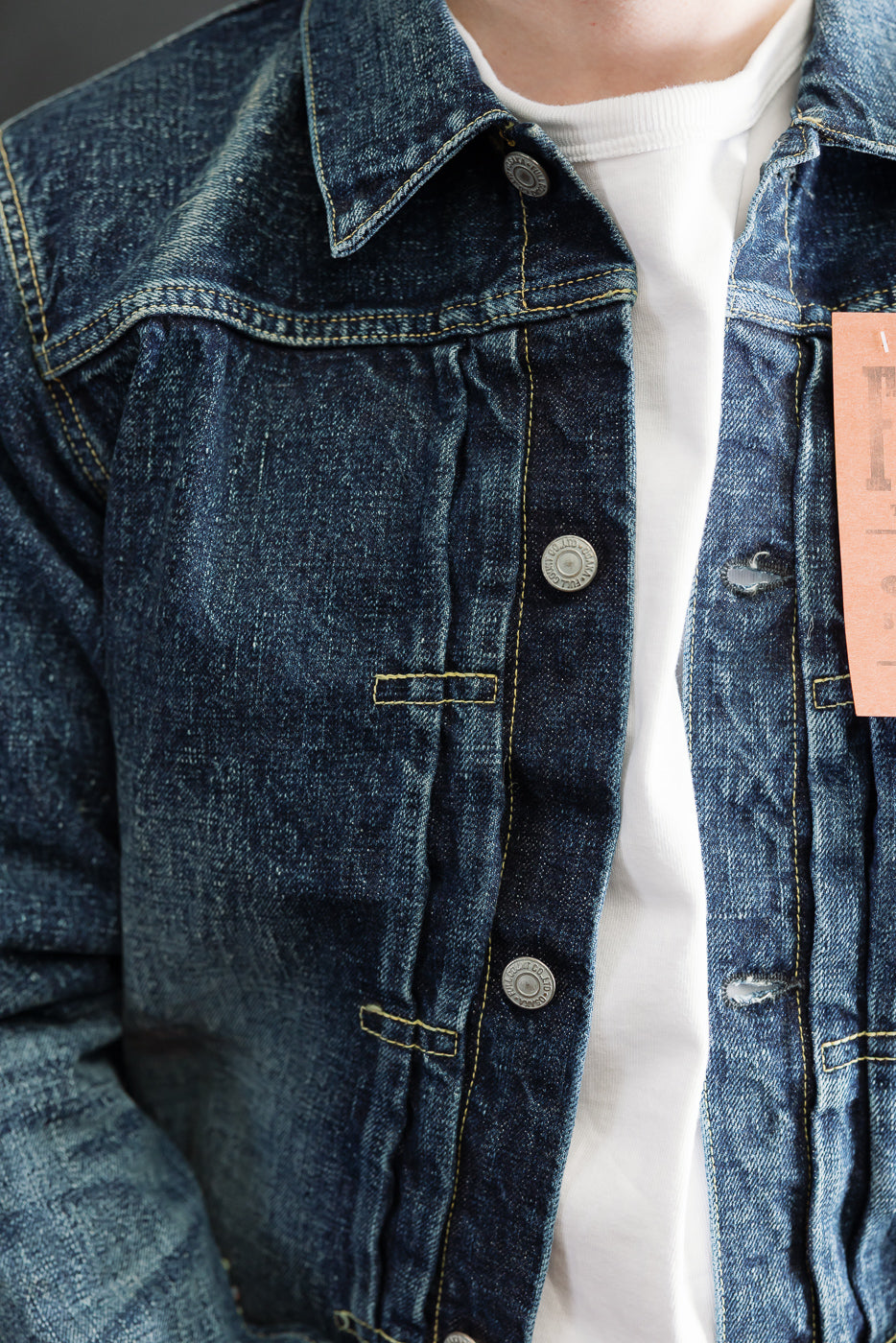 Close-up front view of men's hard washed indigo denim jacket, metal buttons, collar, worn by male model 5'9