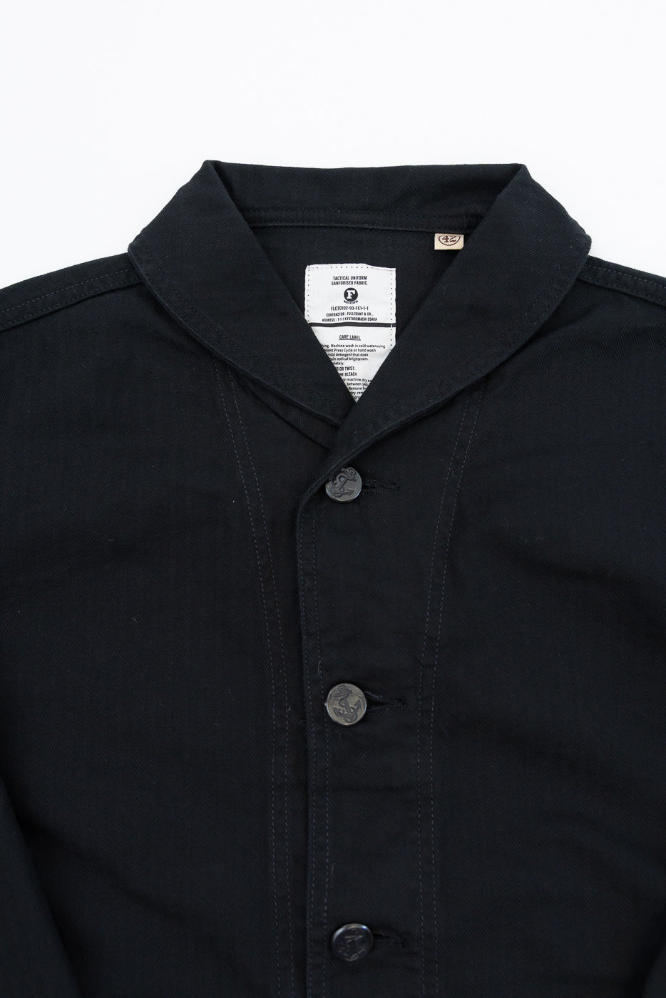 Close-up front view of black shirt with anchor buttons, collar tag, and fabric texture details