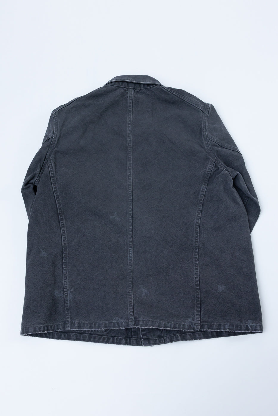 Back view of dark gray denim jacket, flat lay, showcasing hem and seam details