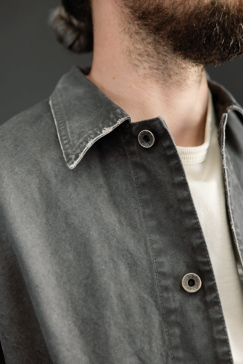 Close-up front view of male model's collar and buttons on dark denim shirt
