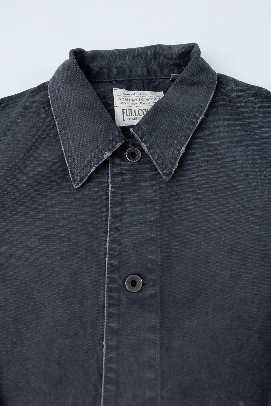 Close-up front view of dark gray shirt collar, buttons, and tag; 100% cotton, athletic wear, sanforized fabric