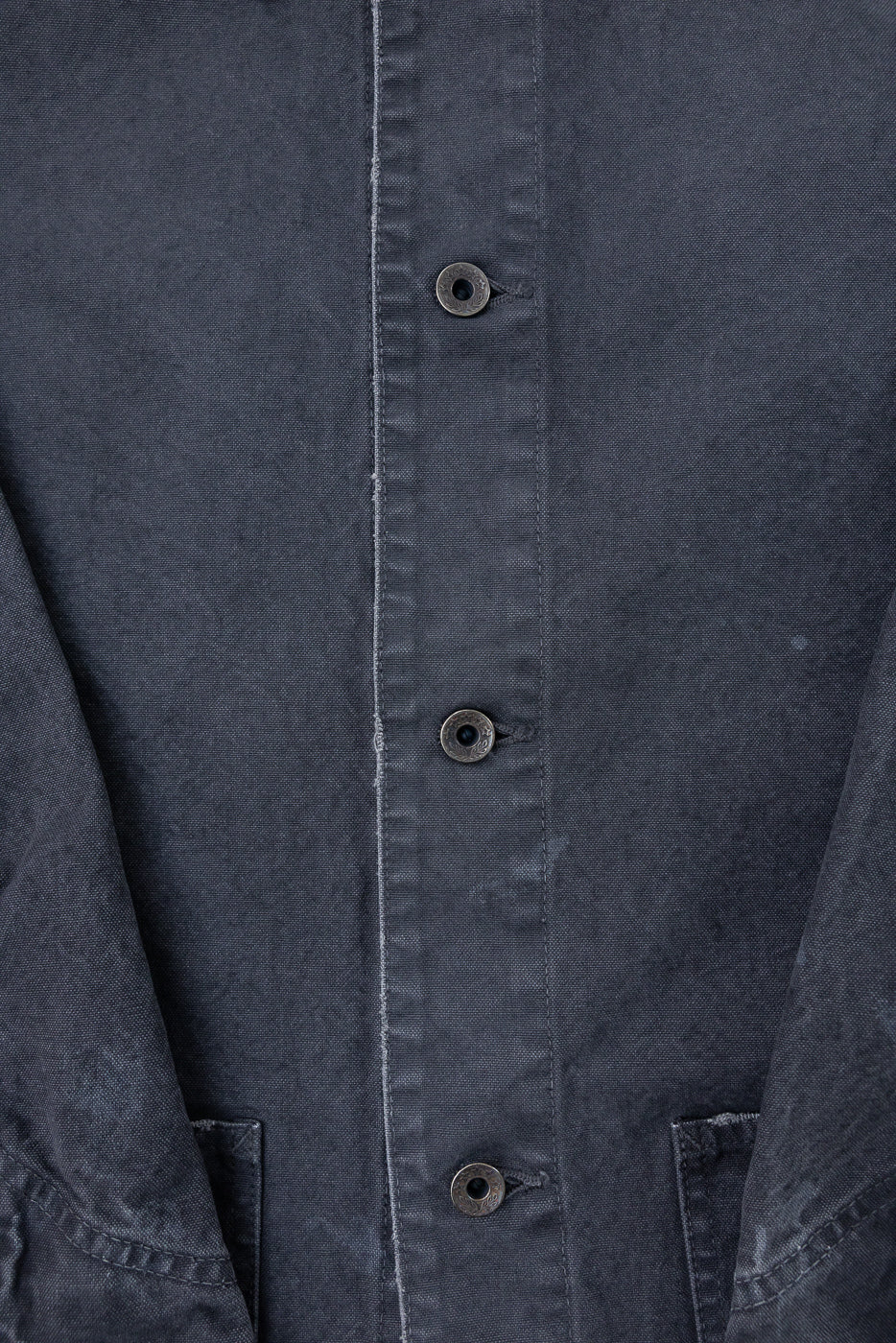 Close-up front view of dark gray chore jacket showing button placket, metal buttons, and fabric texture