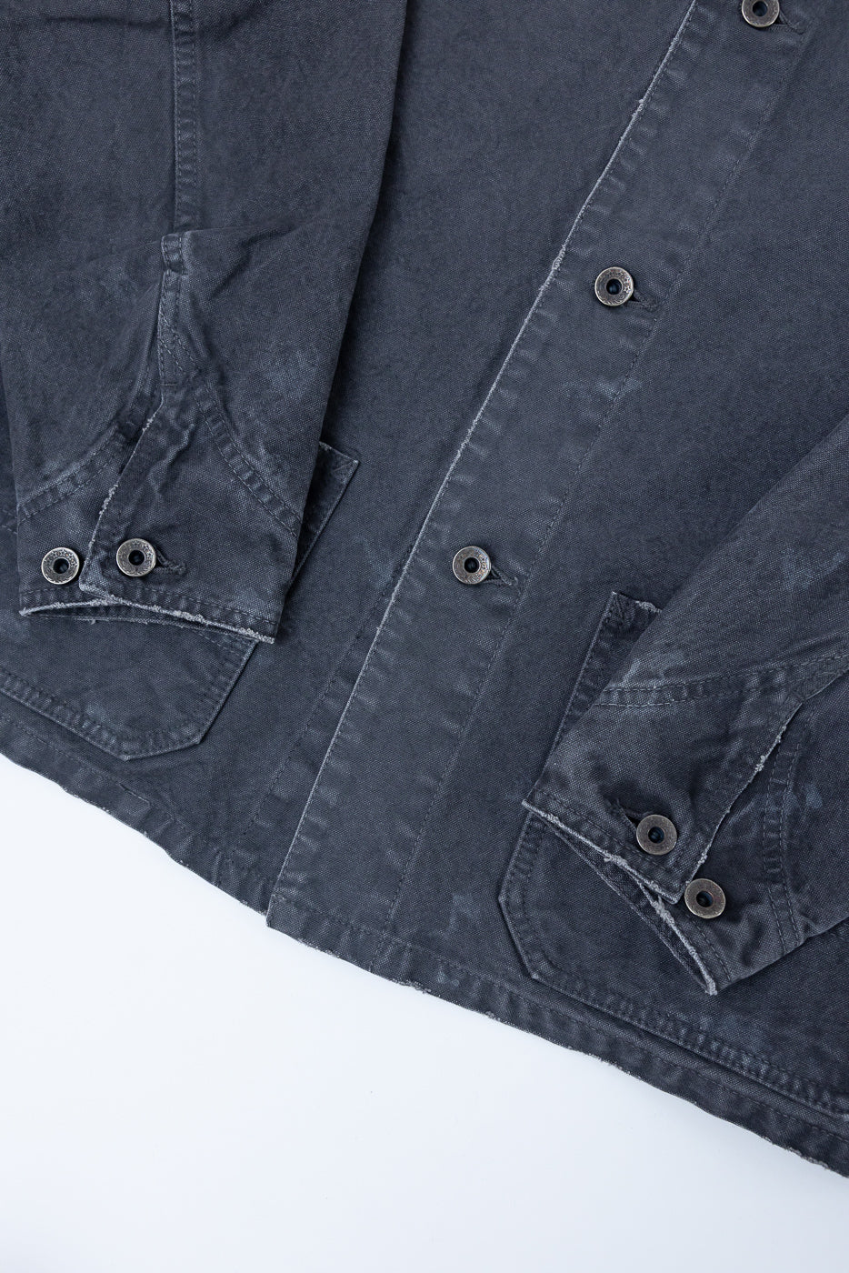 Close-up front view of dark gray selvedge chore jacket, showing button details, chest pockets, and fabric texture
