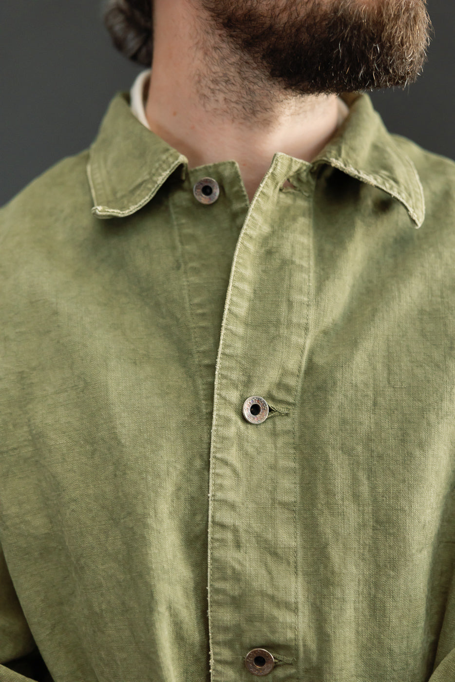 Close-up front view of olive green shirt with button details, worn by male model