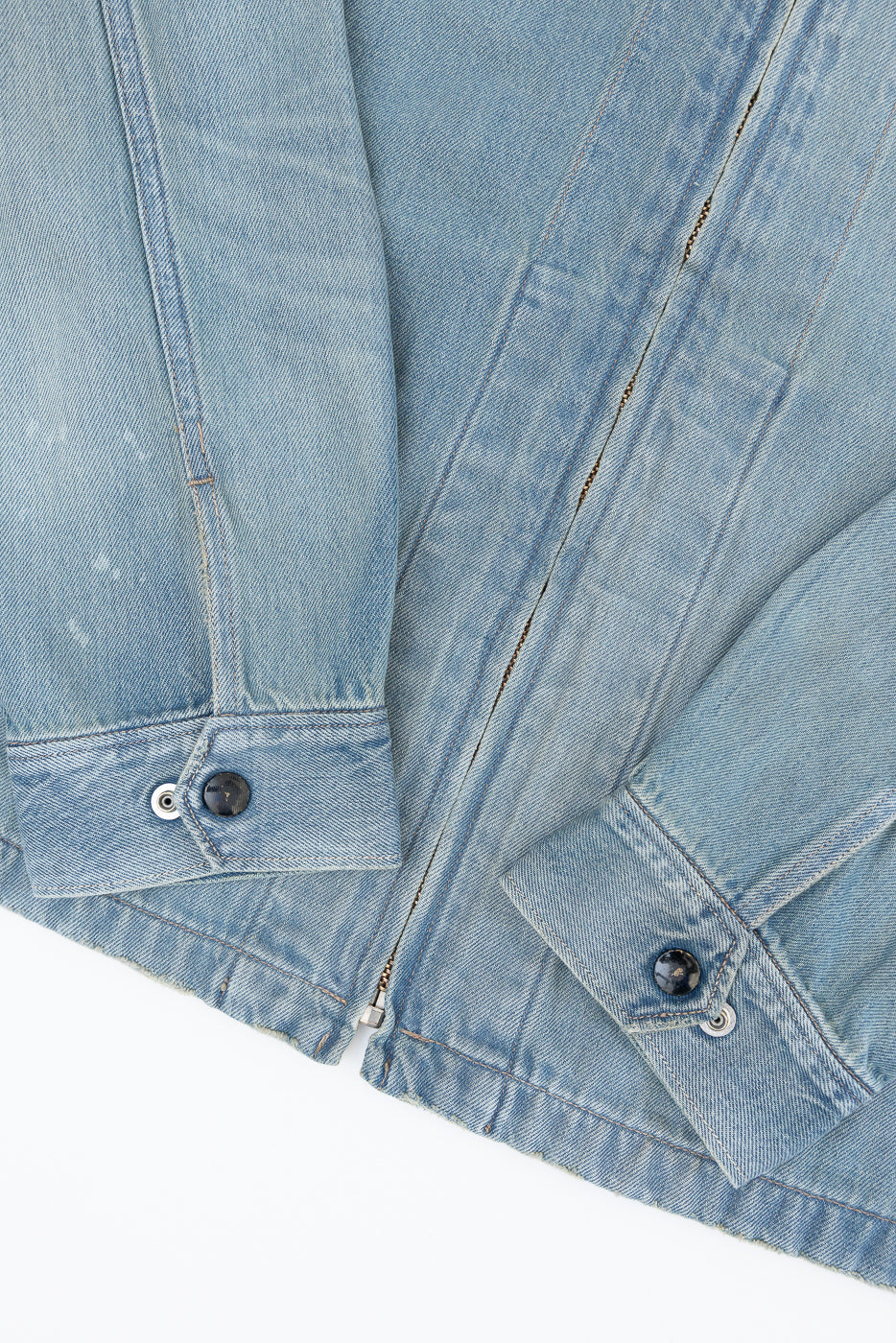 Close-up of light blue denim jacket front, showing button details and fabric texture