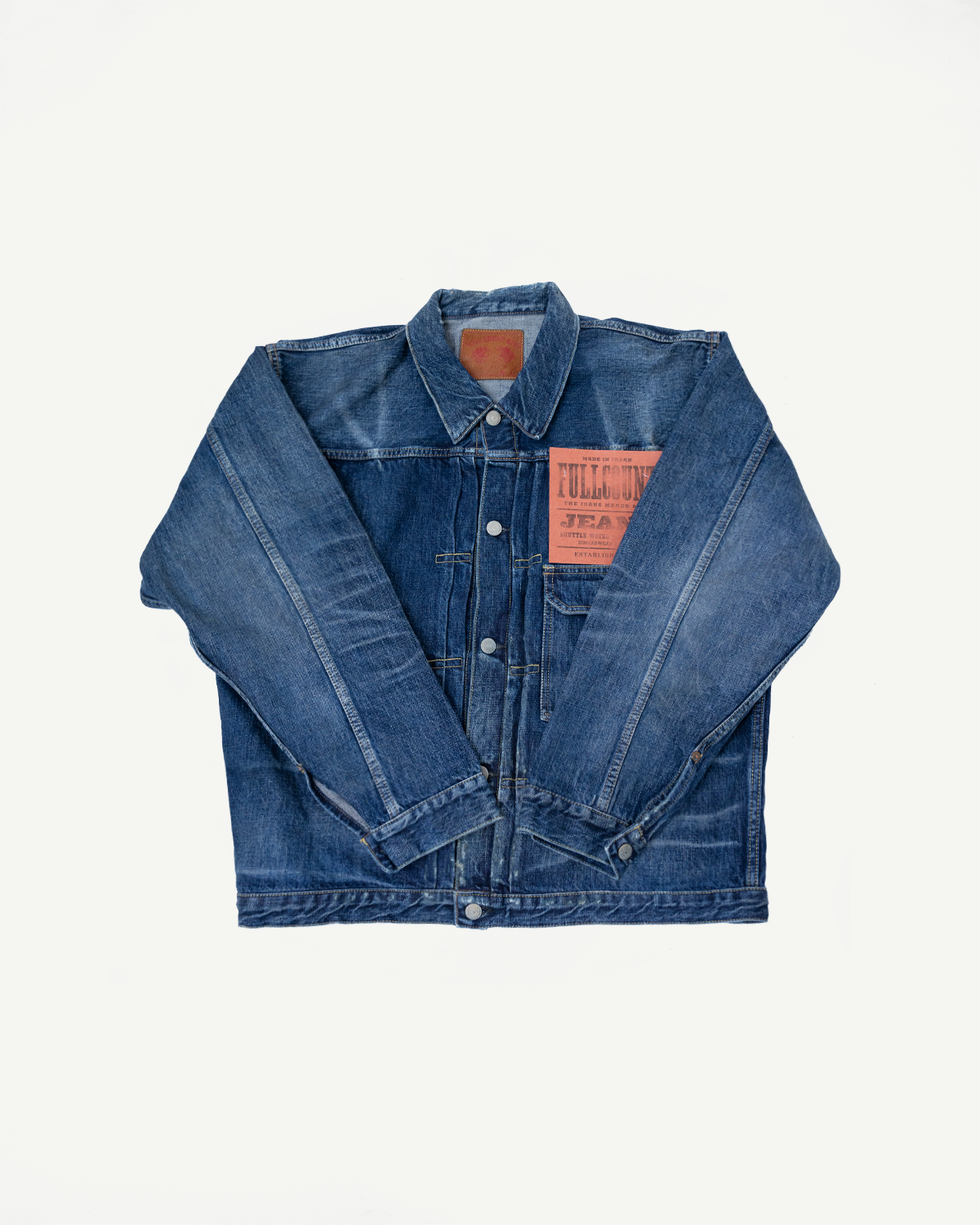 Heavily washed indigo denim jacket with a visible full count label on the left chest pocket on a white background, full lay flat. 