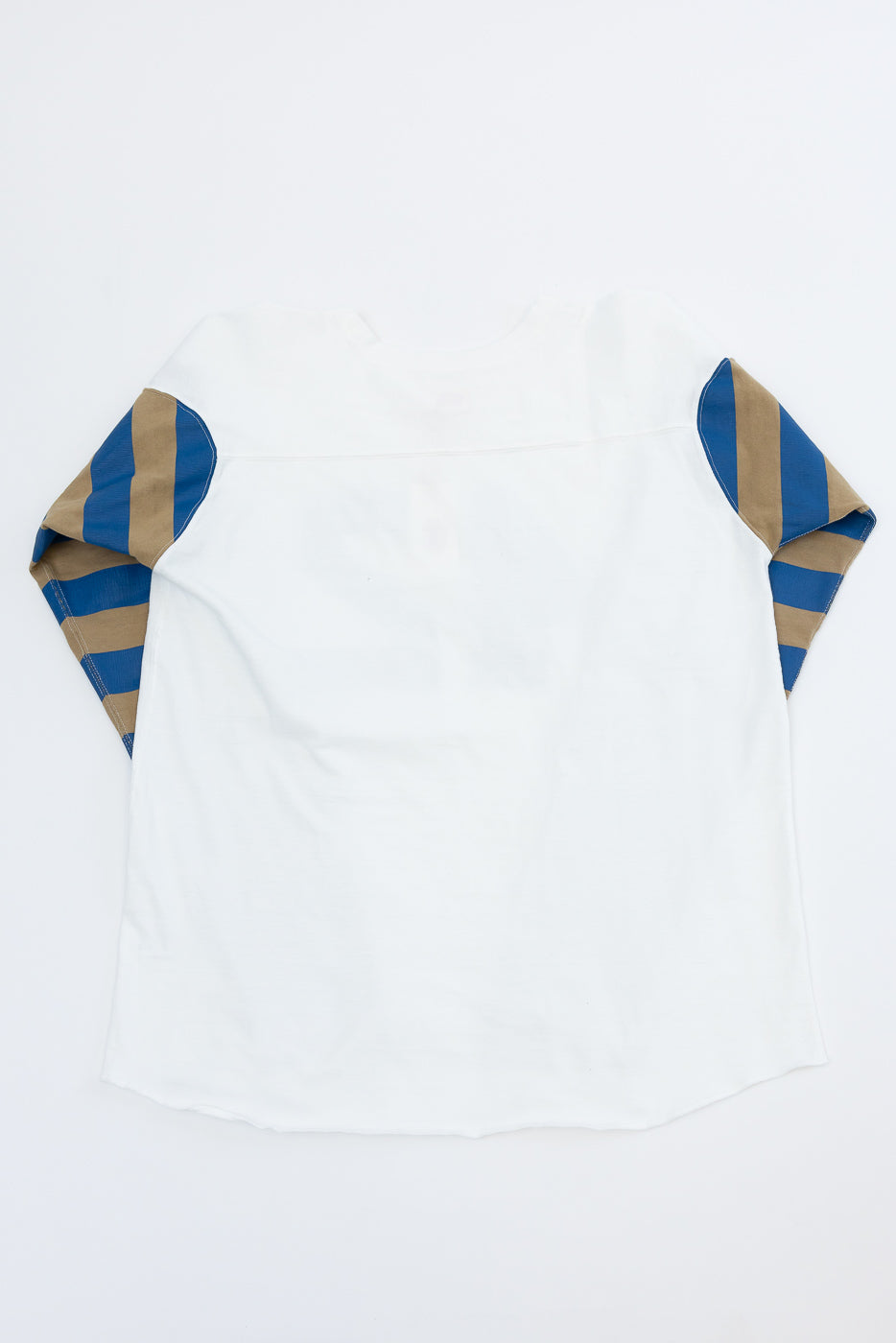 Back view flat lay of white shirt with blue and tan striped raglan sleeves, showing hem and shoulder details