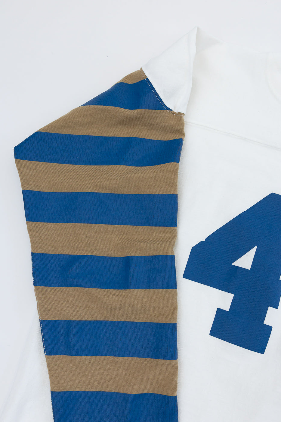 Close-up of striped rugby shirt sleeve, blue and tan horizontal stripes, ribbed texture, white collar detail