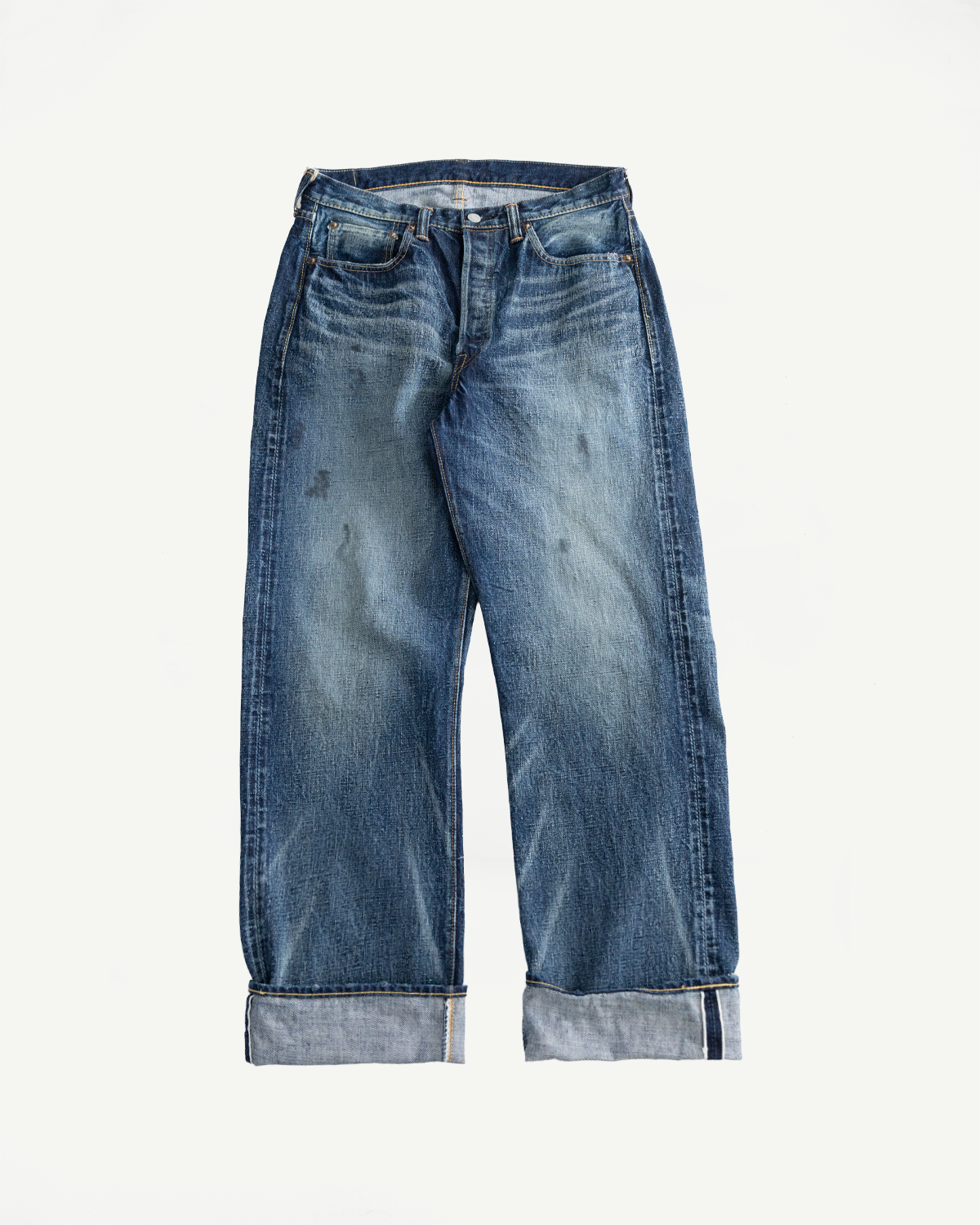 Flat lay of wide-leg hard washed indigo denim jeans, front view, visible cuff and faded texture.