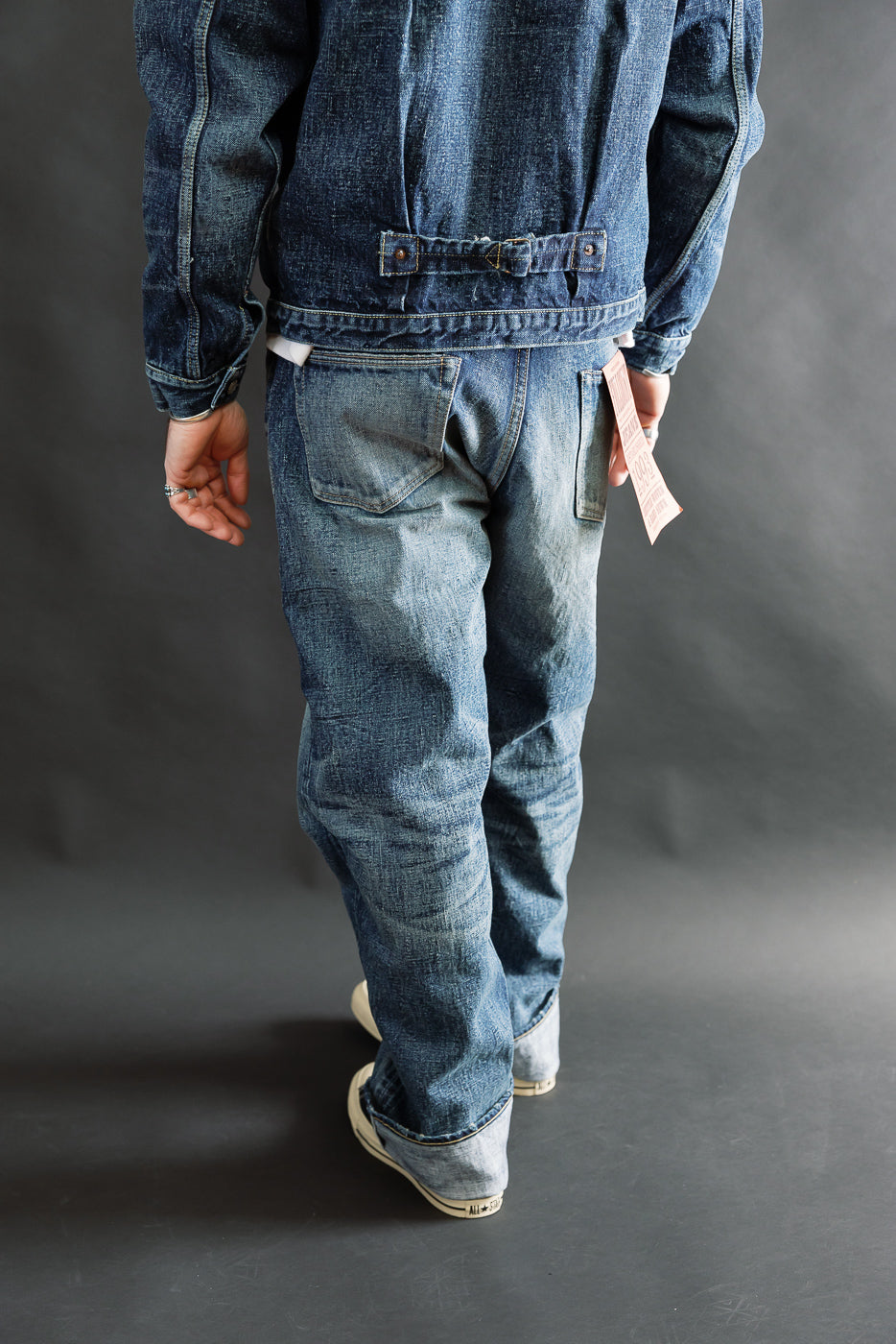 Back view full body of male model 5'9, 165lbs athletic build in hard washed indigo denim jacket and jeans, showing fit, rear pockets, and fabric texture.