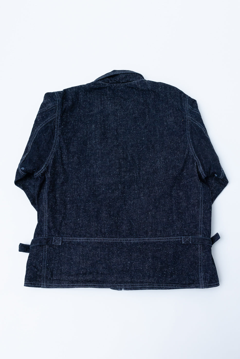 Back view flat lay of dark selvedge denim jacket, showing collar, sleeve cuffs, and hem details