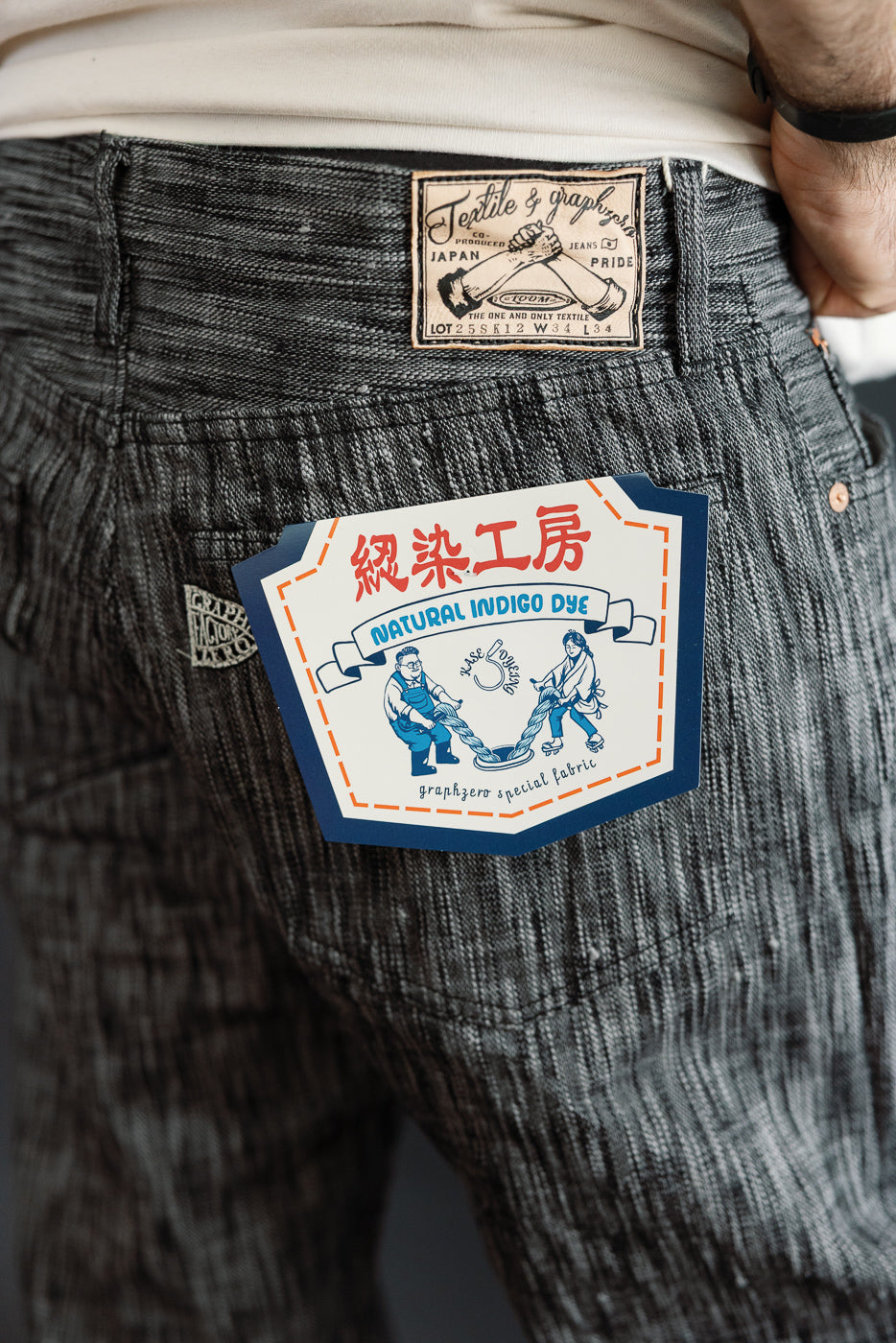 Close-up back view of men's selvedge jeans showing natural indigo dye tag, athletic build model, 5'9
