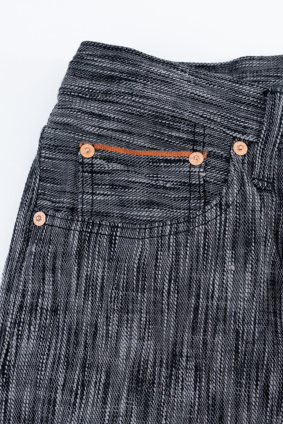 Close-up front view of selvedge jeans with copper rivets and orange stitching detail