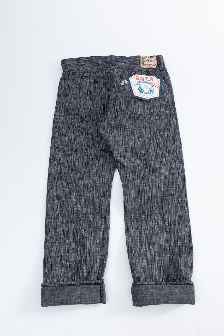 Back view of selvedge jeans with cuffed hems and branded patch, flat lay
