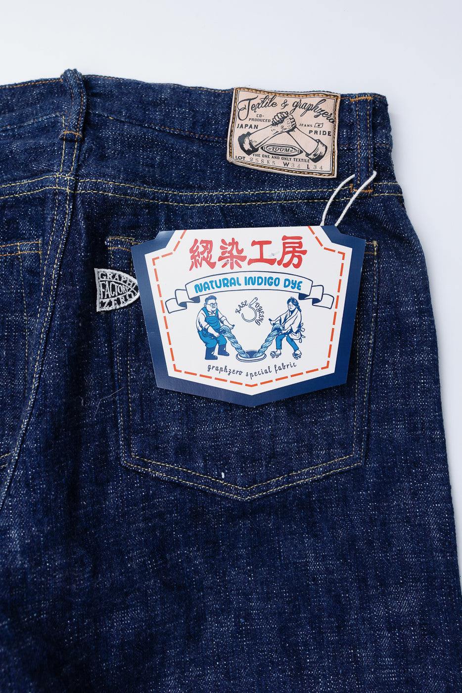 Close-up of back of Graph Zero 15oz indigo selvedge jeans showing rear pocket, tag, and leather patch.