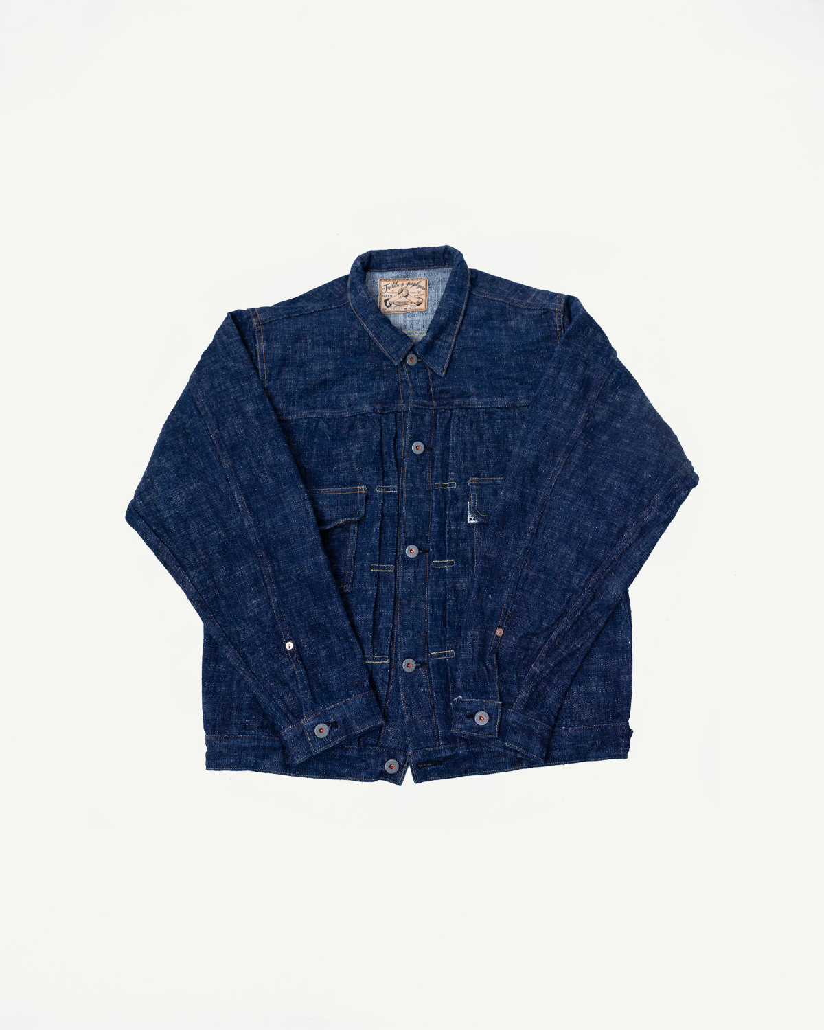 Front flat lay of Graph Zero 15oz skein-dyed slubby blue indigo selvedge Type II denim jacket featuring chest pockets, metal buttons, pointed collar, and visible textured fabric, from Dant casual apparel.