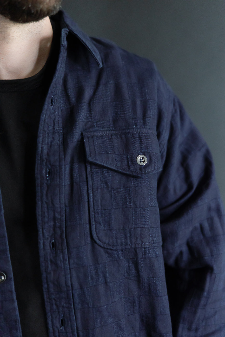 Close-up front view of navy quilted shirt, male model, athletic build, chest pocket with button detail