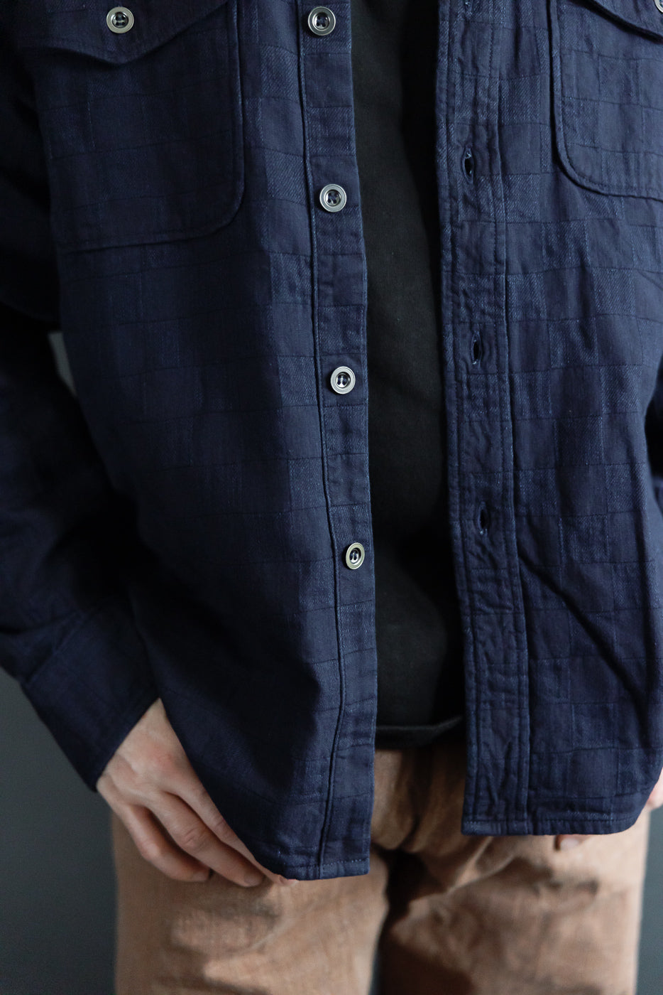 Close-up front view of navy quilted shirt with silver buttons, worn by male model, 5'9