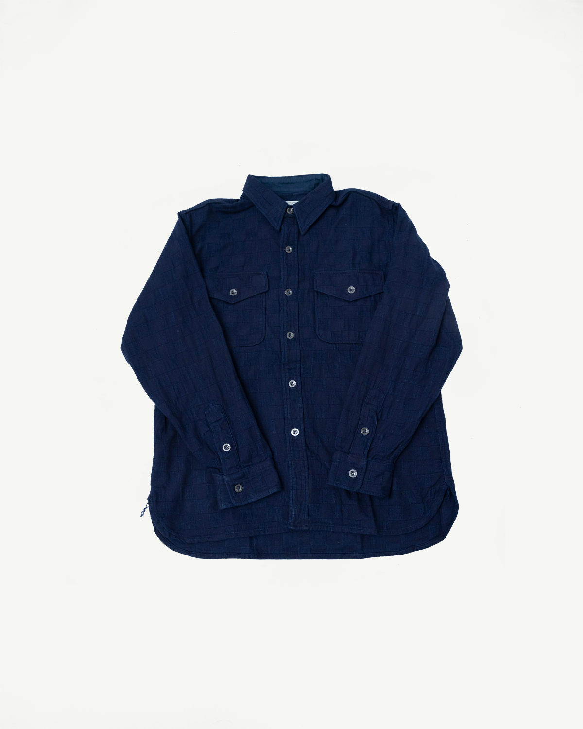 Navy blue long-sleeve shirt flat lay, front view. Features button-down collar, two chest pockets, and button cuffs. Textured fabric.
