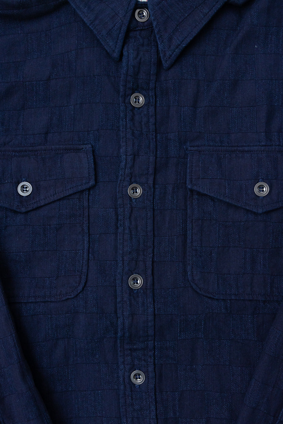 Close-up front view of navy quilted shirt with button-down collar, chest pockets, and silver buttons