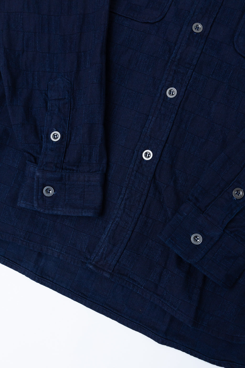 Close-up front view of navy blue checkered shirt with button details and textured fabric