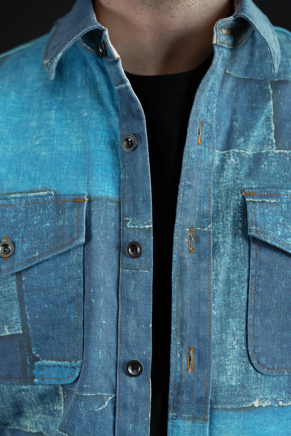 Close-up front view of male model wearing distressed denim shirt with button details and chest pockets