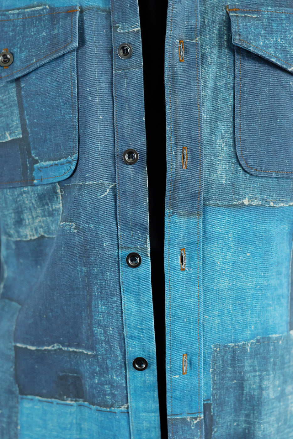 Close-up front view of patchwork denim shirt with button placket, chest pockets, and distressed texture