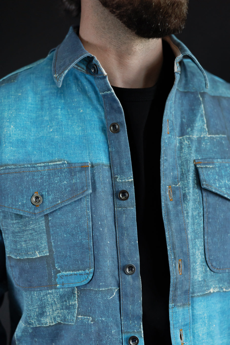 Close-up front view of male model wearing distressed denim shirt with button details and chest pockets