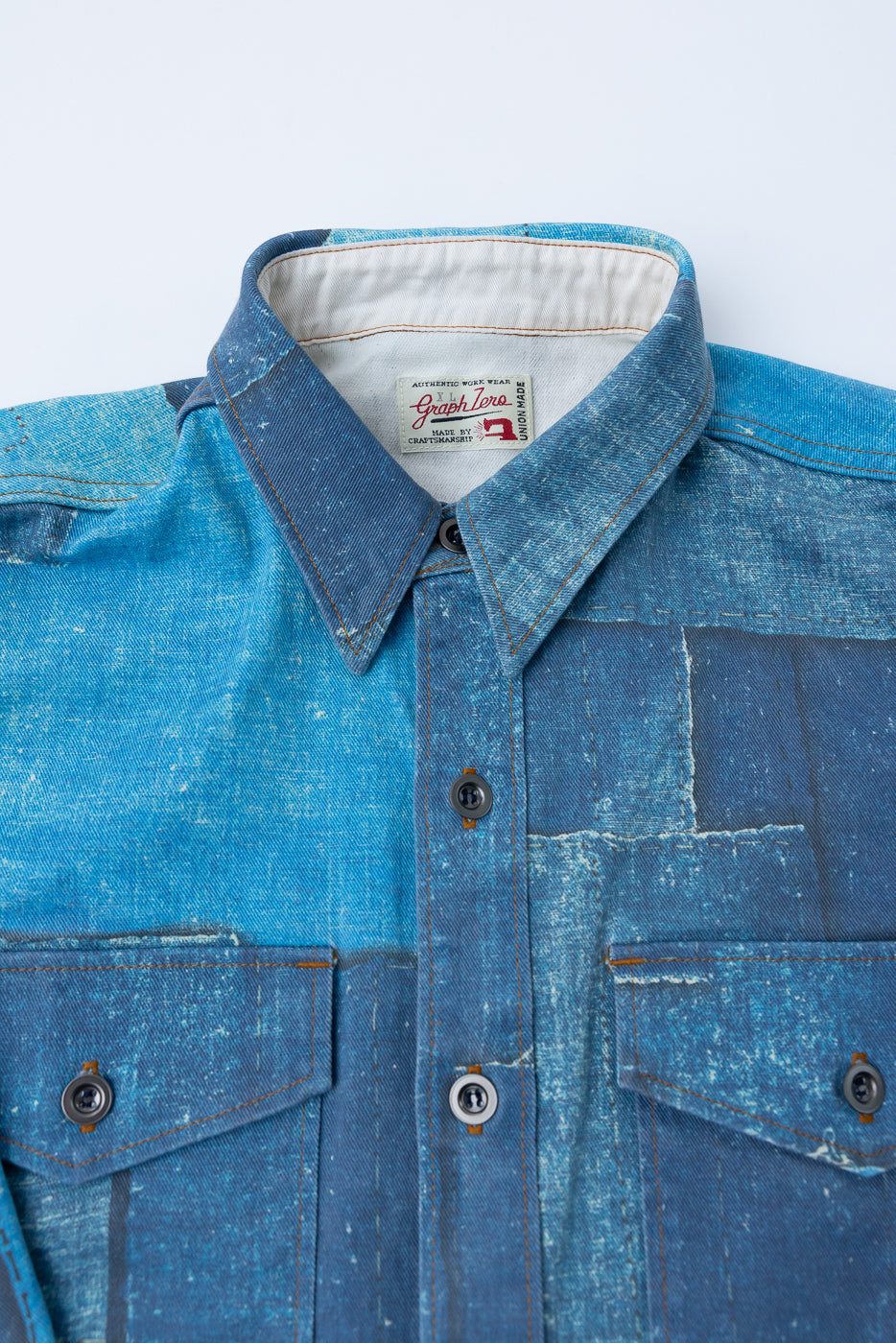 Close-up front view of blue patchwork denim work shirt, collar tag, buttons, and chest pockets visible