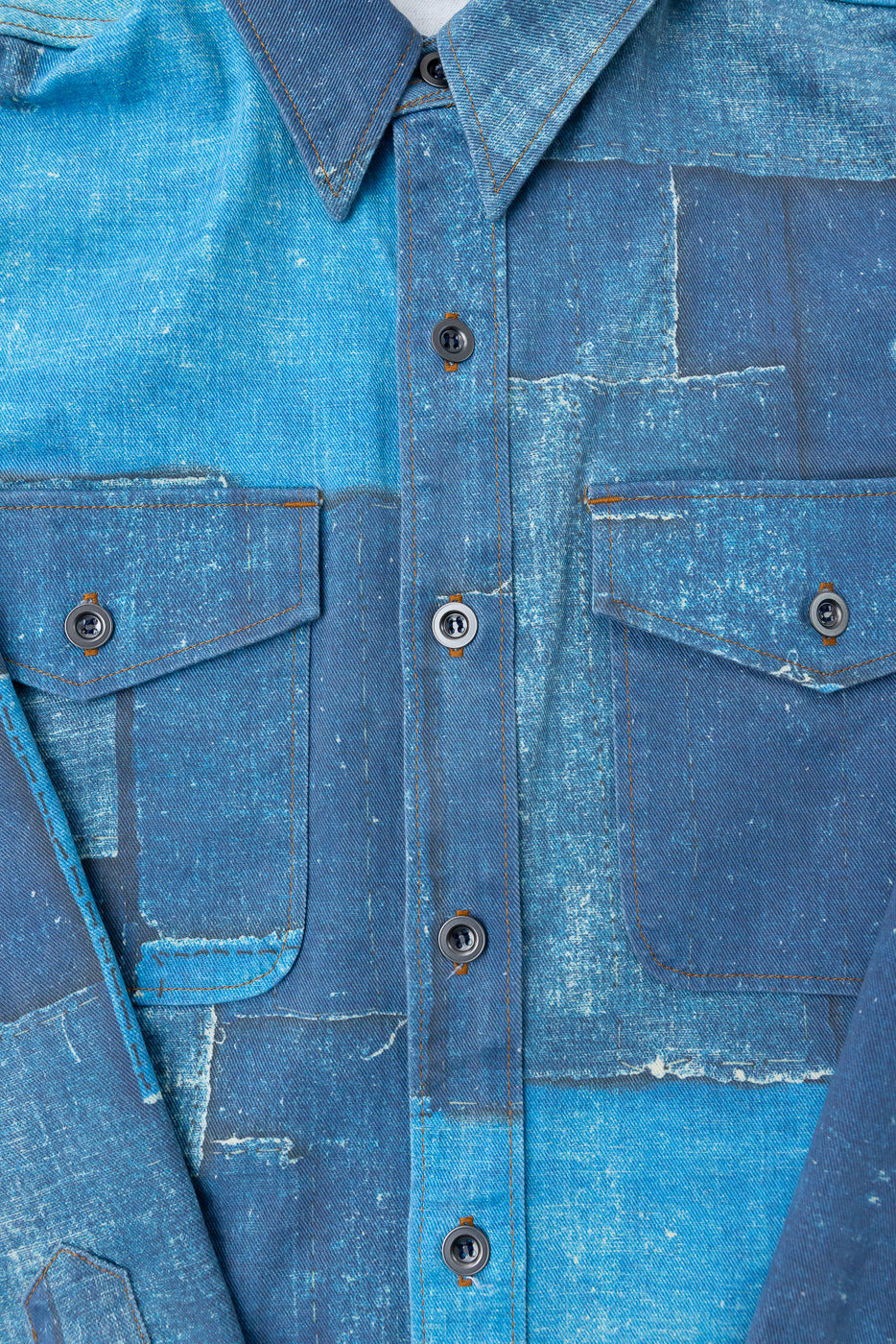 Close-up front view of distressed denim shirt with button-down collar, chest pockets, and contrast stitching