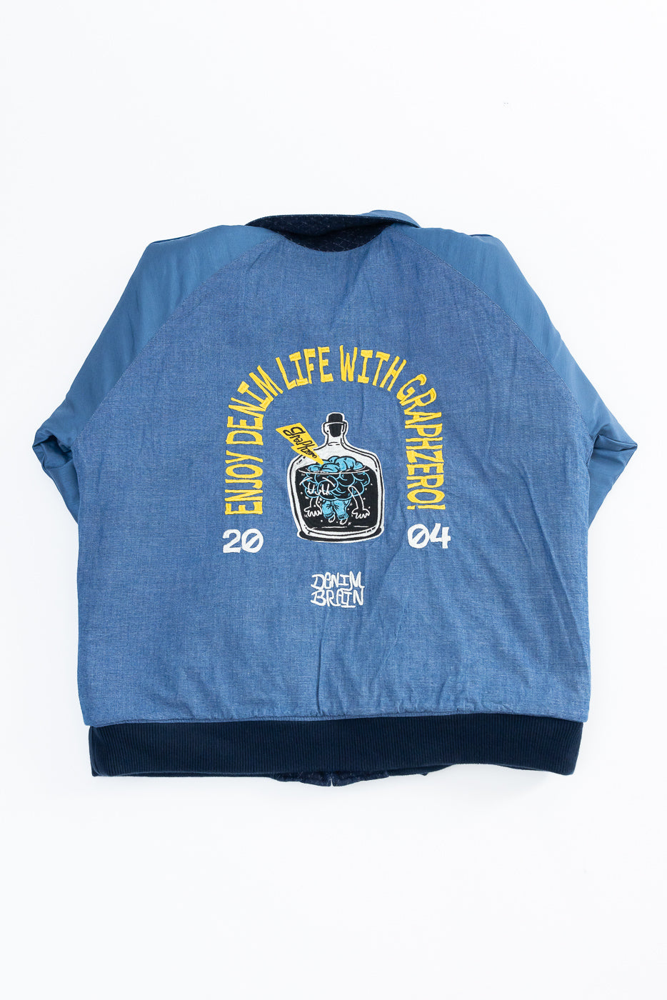 Back view flat lay of blue denim bomber jacket with 'Enjoy Denim Life' graphic, raglan sleeves, and ribbed hem.