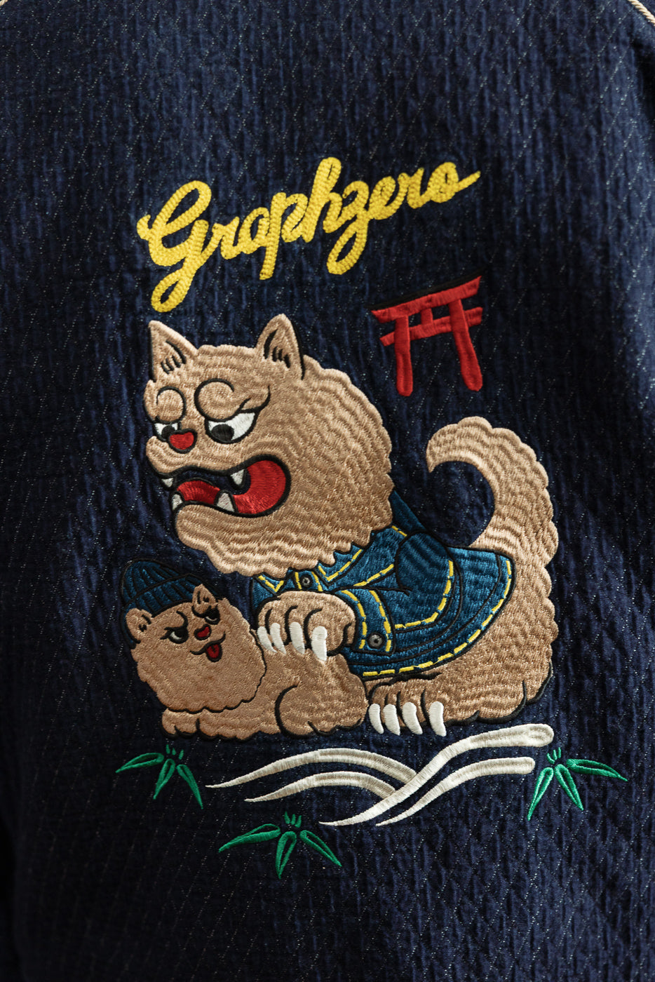 Close-up front of navy jacket with embroidered cat graphic, 'Graphzero' text, and bamboo details