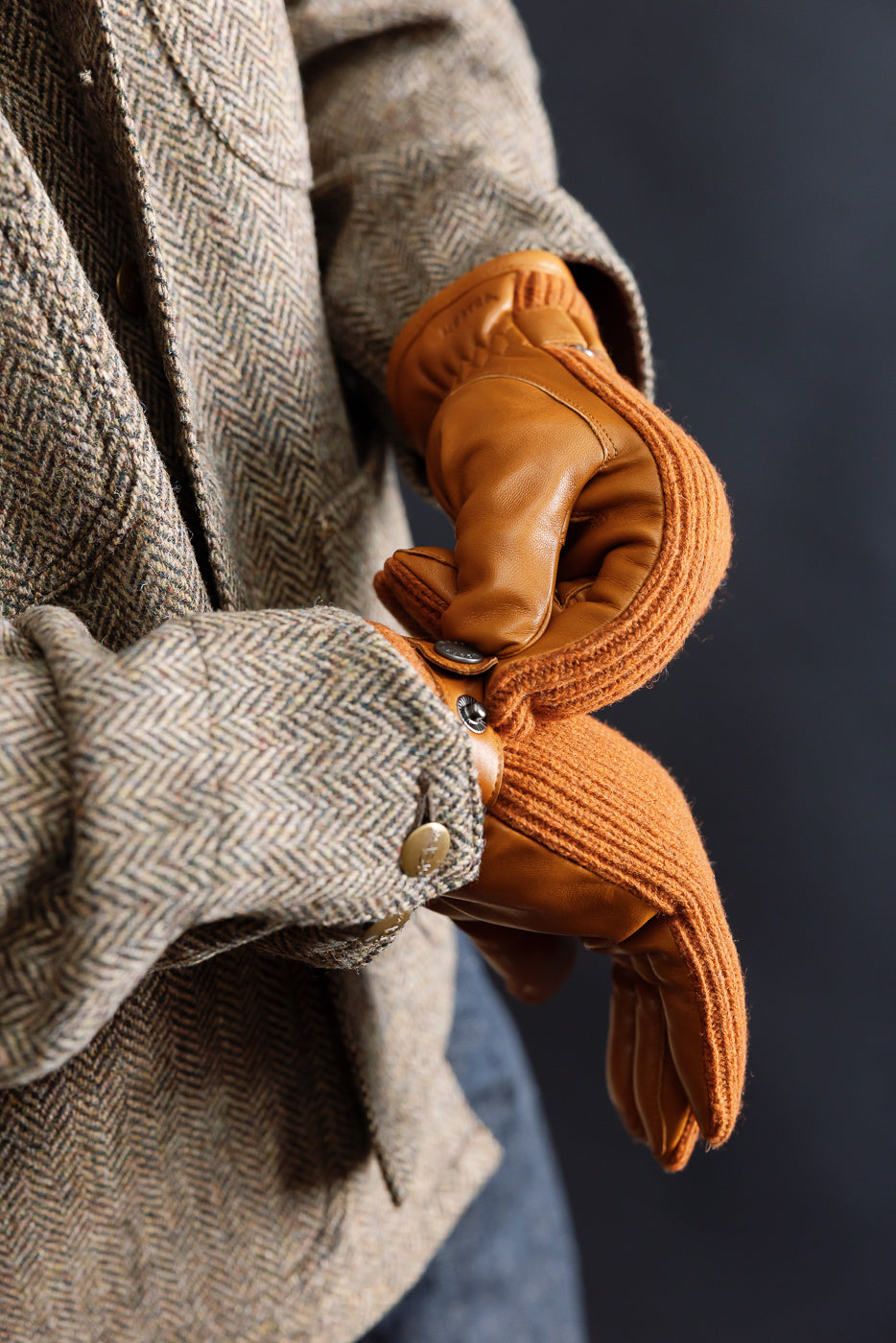 Close-up of Hestra Christopher cork gloves on male model, front view, showing glove texture and button detail, styled with herringbone jacket at Dant Indianapolis.