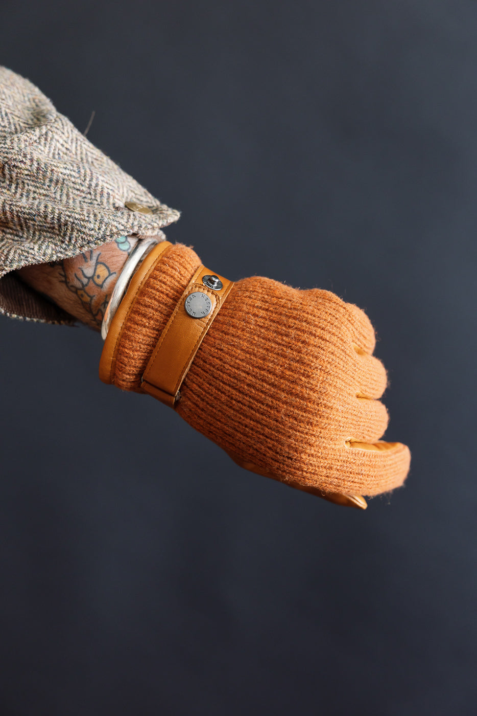 Close-up of Hestra Christopher glove in cork, ribbed knit texture, leather strap, on male model’s left hand.