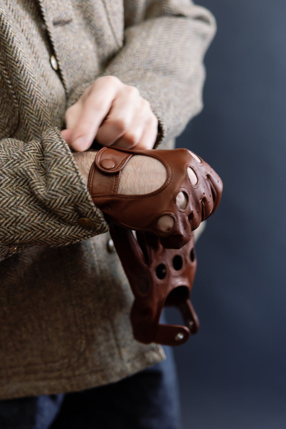 Close-up of chestnut brown Hestra Morgan driving glove on male model, showing button wrist detail.