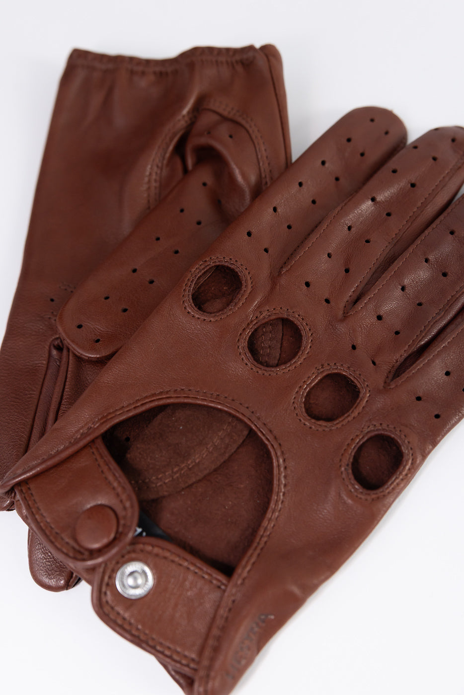 Close-up of Hestra Morgan chestnut brown leather driving gloves, front side, perforated details, snap closure.