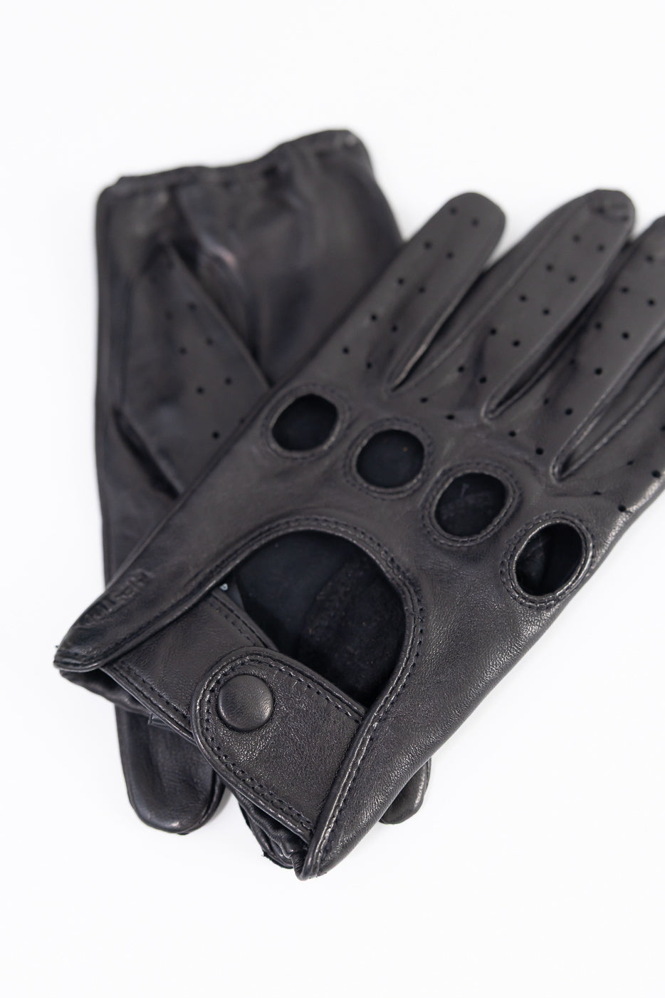 Close-up of Hestra Morgan black leather driving gloves, front side, with snap closure and knuckle holes, Dant accessories.