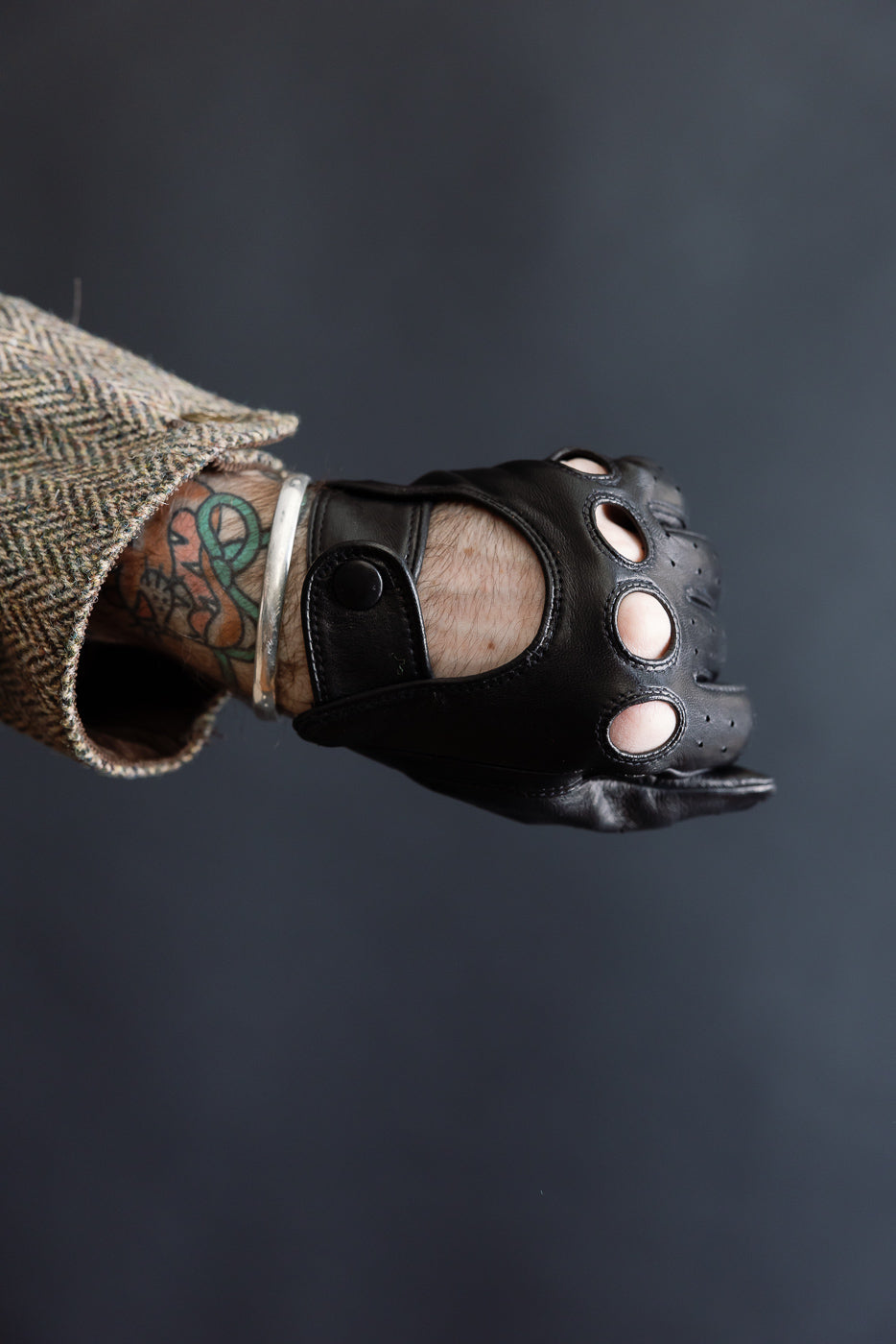 Close-up side view of black leather Hestra Morgan driving glove on male model, showing knuckle cutouts and snap closure, Dant contemporary accessories