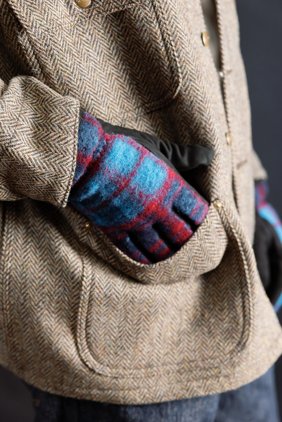 Close-up of Hestra Noah plaid glove in navy and red on male model, front jacket pocket detail