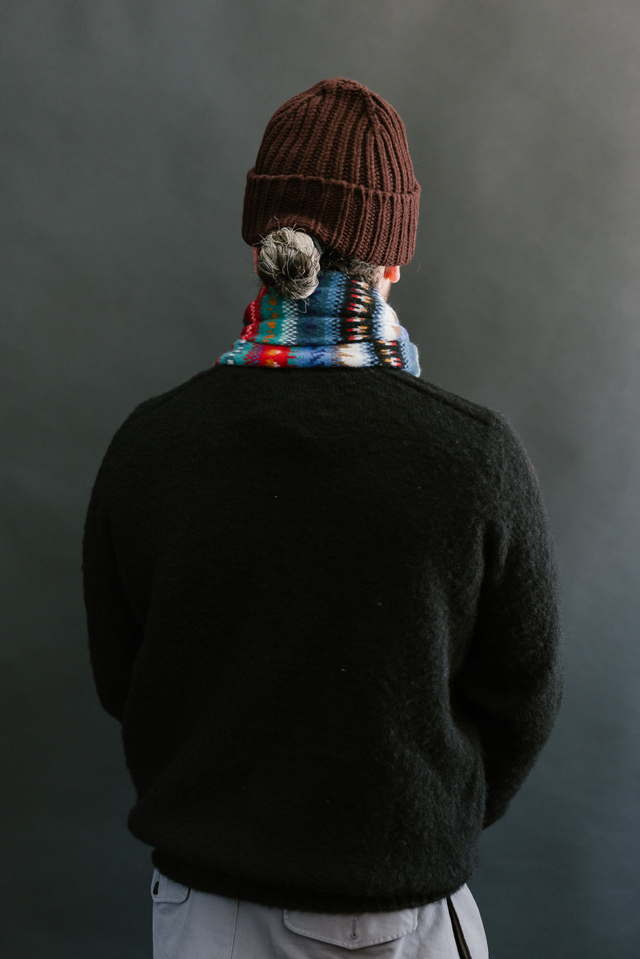 multicolored, patterned wool scarf with a black base on bearded man with a black sweater, back view