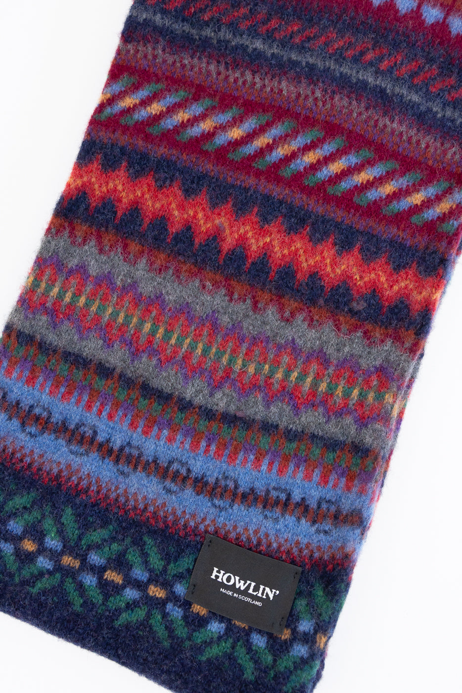 multicolored, patterned wool scarf with a navy base on a white background, close up
