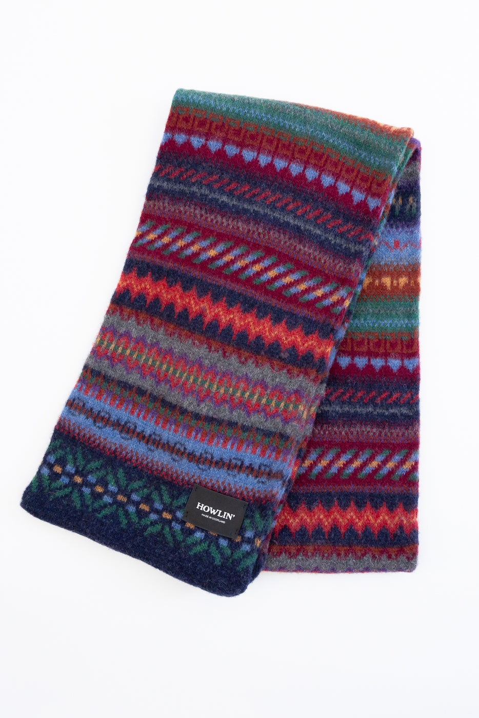 multicolored, patterned wool scarf with a navy base on a white background exposing back side of scarf
