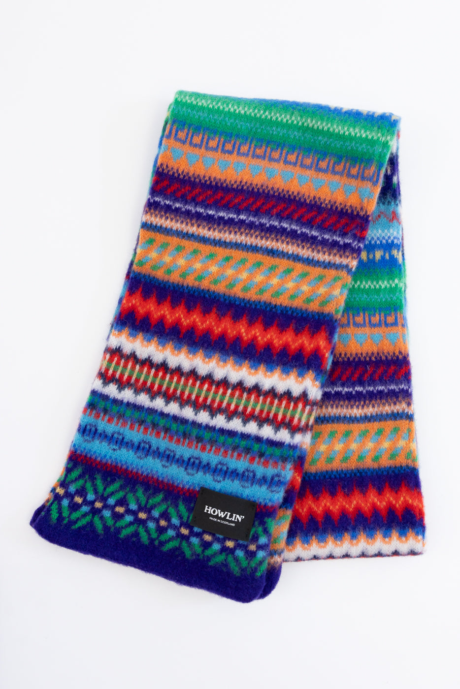 multicolored, patterned wool scarf with a purple base on a white background exposing back of scarf