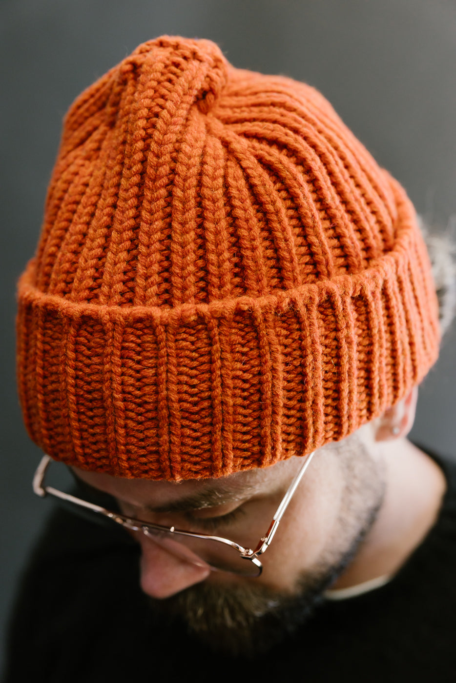 safety orange ribbed chunky beanie, watch cap on bearded mans head, close up