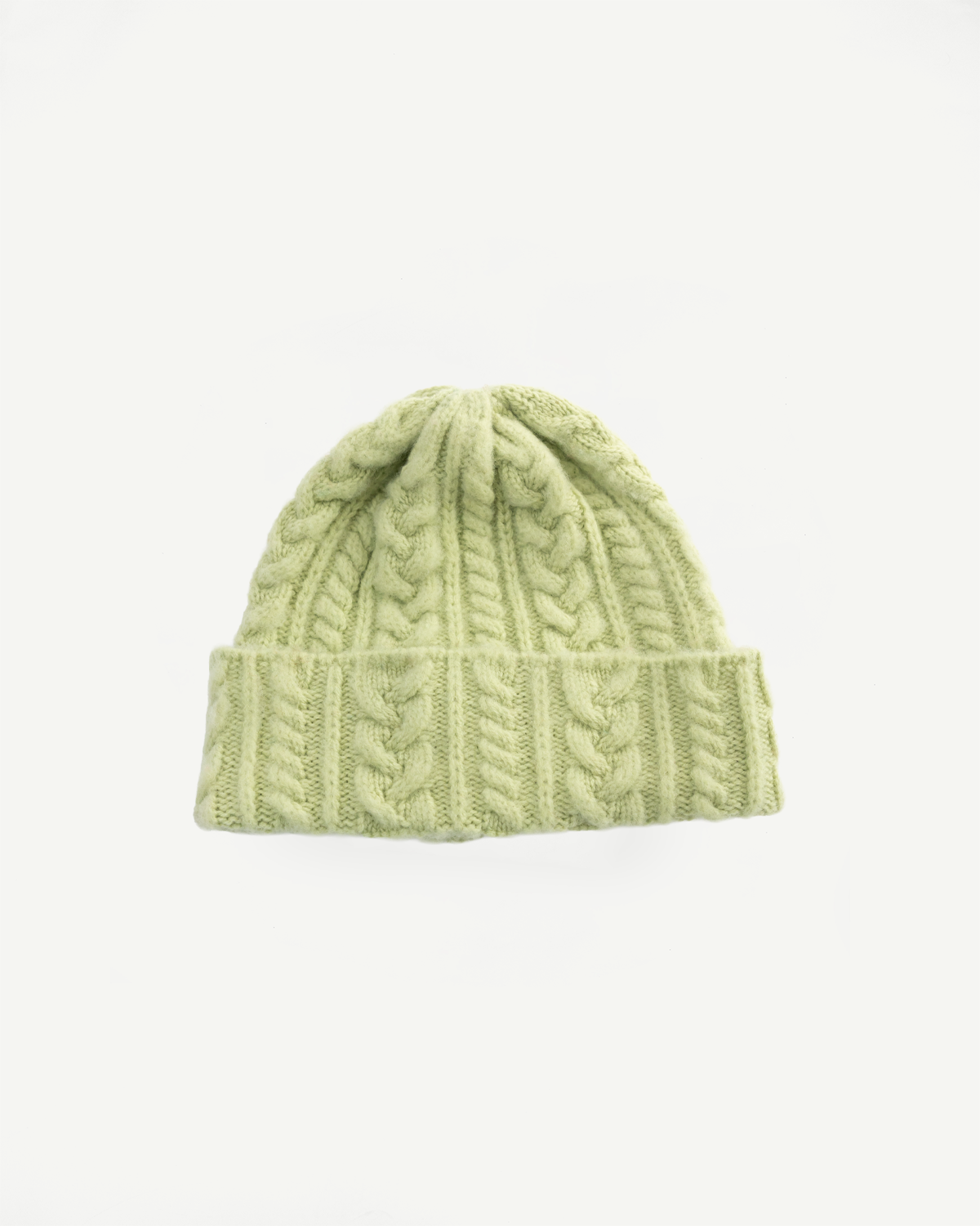 Flat lay front view of soft green cable knit beanie hat, showcasing texture and folded brim.