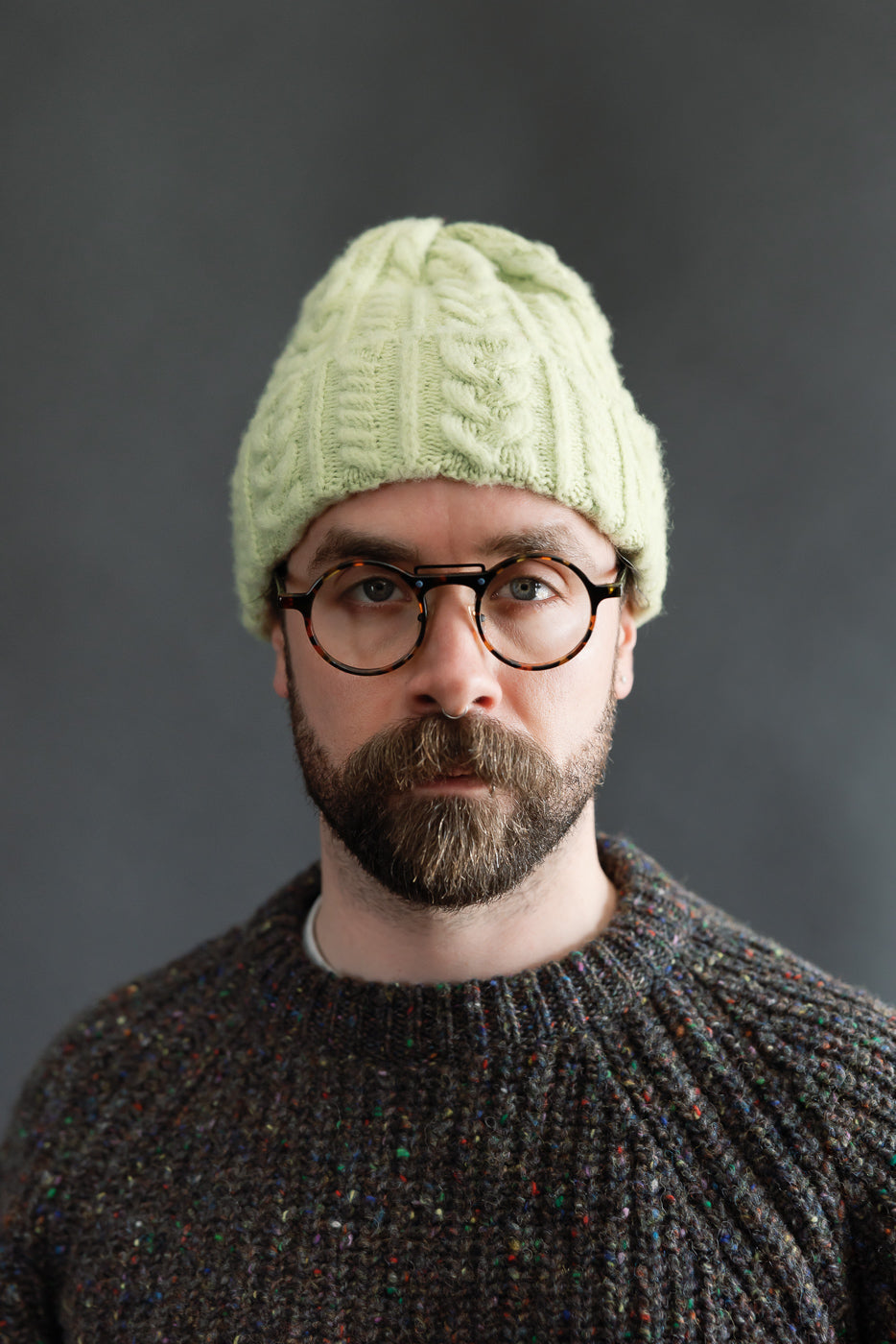 Front close-up of soft green cable knit beanie on male model, 5'9