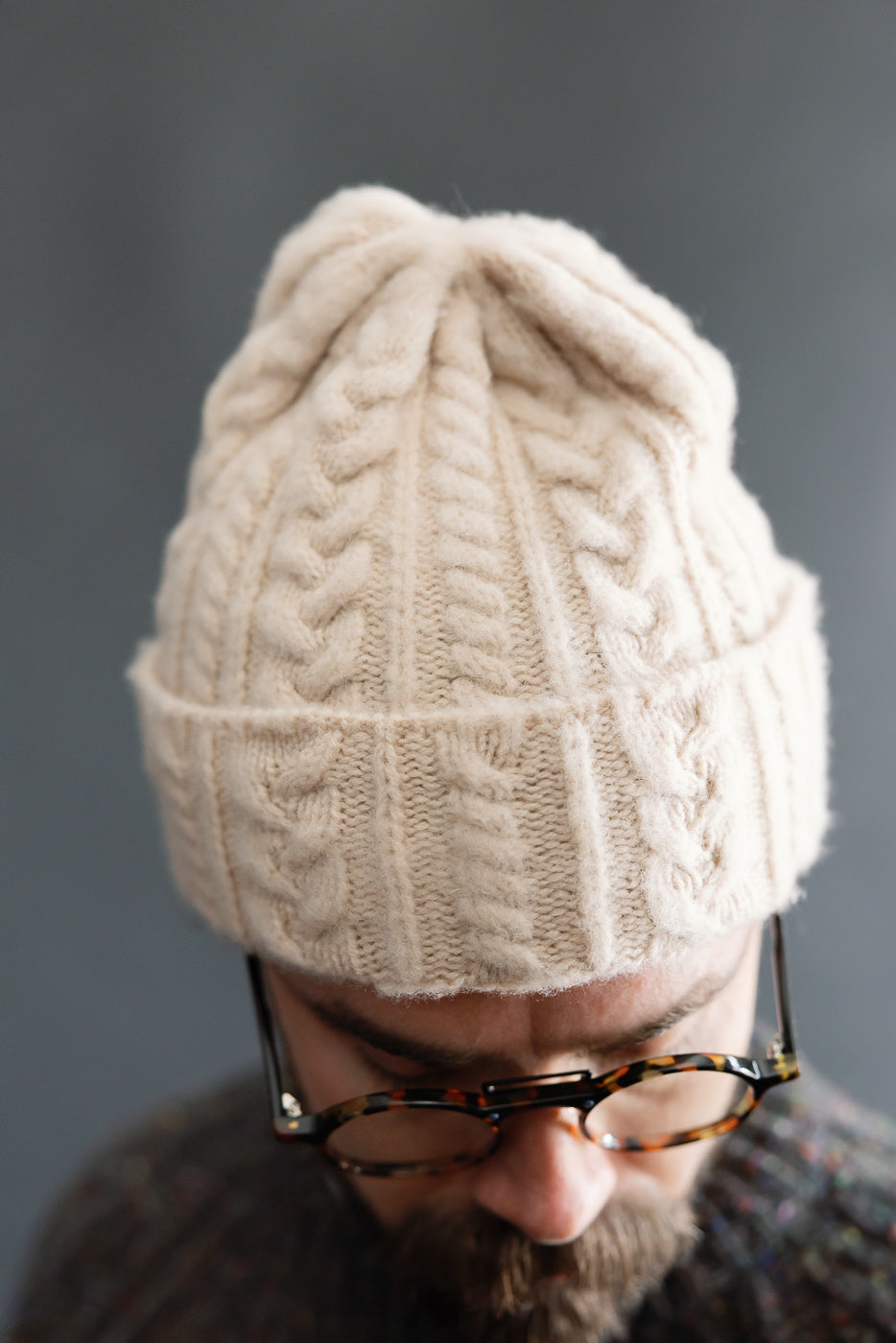 Close-up front view of soft oatmilk cable knit beanie on male model, 5'9