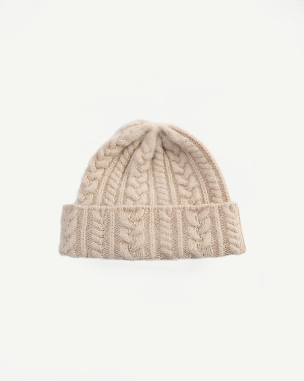Front view flat lay of Howlin cable knit hat in soft oatmilk, showing texture and folded cuff.